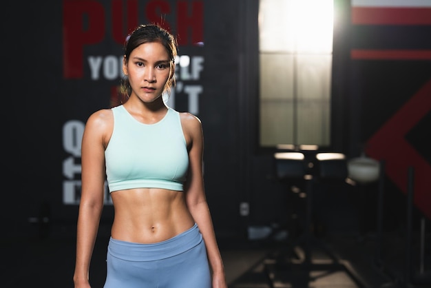 Asian athlete woman in sportswear slim muscular body posing after exercise in fitness gym