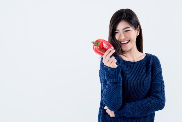 Asian attractive woman is good shape holding and looking at a red vegetable bell pepper