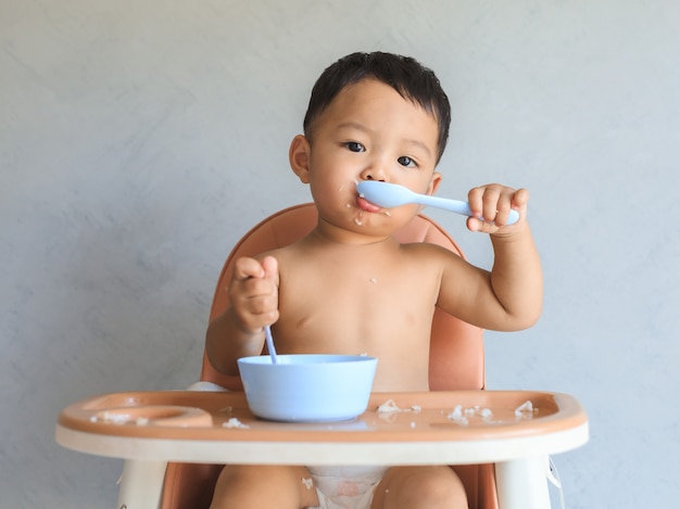 혼자서 음식을 먹는 아시아 아기