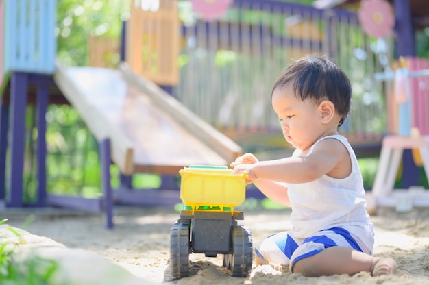 砂場で砂で遊ぶアジアの男の子。健康的なアクティブな赤ちゃんは屋外でおもちゃを再生します