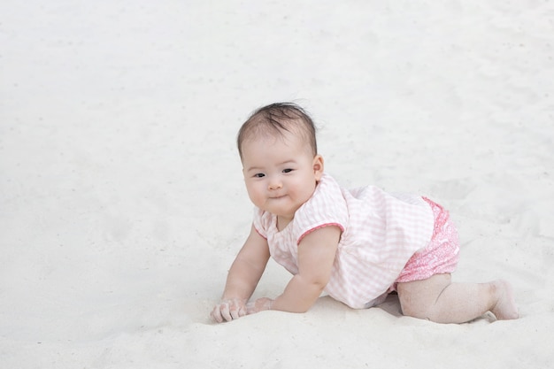 Foto bambino asiatico che striscia sulla sabbia