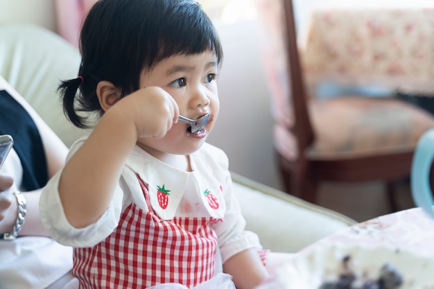 Asian baby eating chocolate cake in the cafe