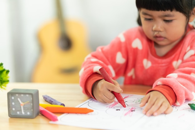 Asian baby girl drawing with colourful crayon , happy funny child girl draws laughing, training, development, abilities. childs art concept