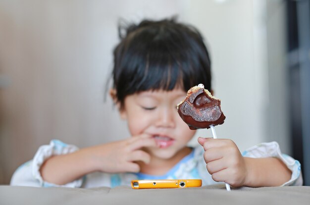 Asian baby girl eating donut in room. Childhood.