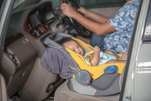 Asian baby girl sits on a car seat On the seat of the car where the father is the driver for safety