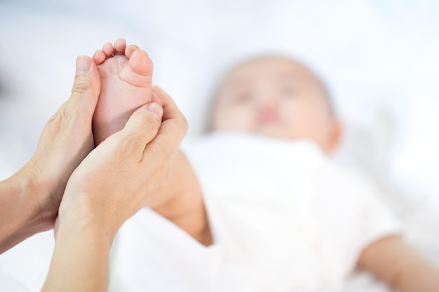 Bambino asiatico felice nella stanzabambina asiatica sdraiata sul letto mothe tenere piede bambino