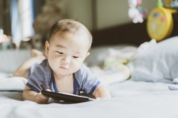 Il bambino asiatico sta imparando e guardando contenuti e social media sul cellulare.