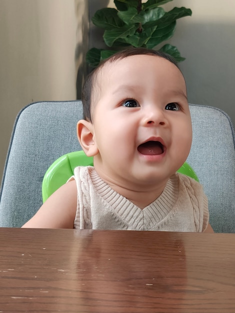 Asian baby laughing, Wow face sitting on a chair