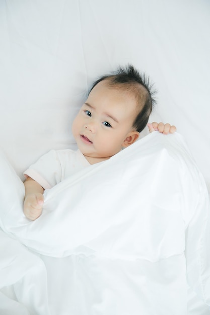 Азиатский ребенок лежит на кровати с мягким одеялом в помещении милый маленький азиатский новорожденный ребенок