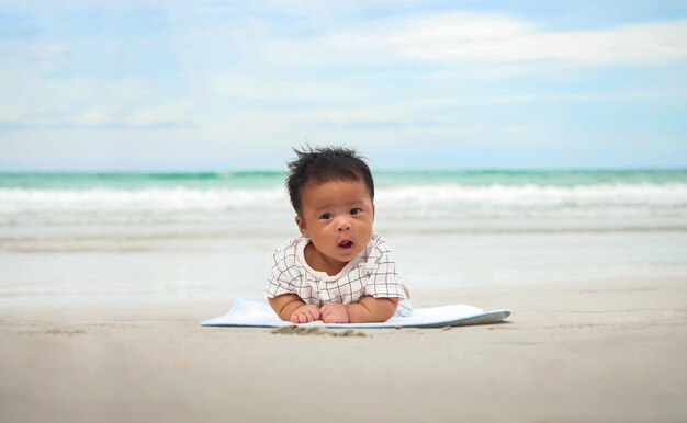 Asian baby lying on the stomach at the beach and nice blue sky