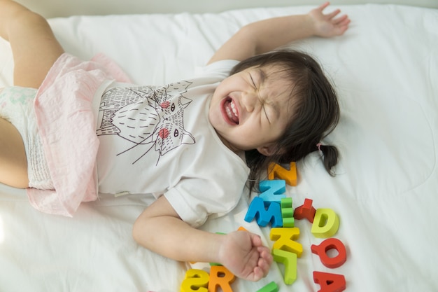 アジアの赤ちゃんがベッドの上でABCの手紙を遊んで