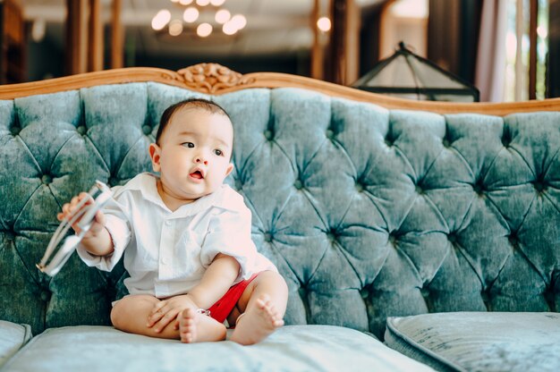 ソファ、夏のファッションのコンセプトに座っているアジアの赤ちゃん