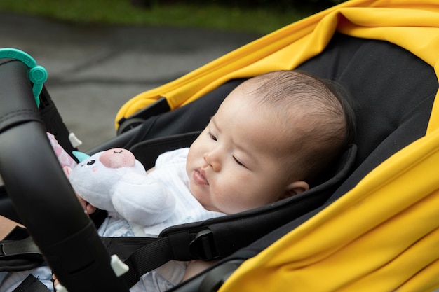 Sonno asiatico del bambino dentro il passeggiatore