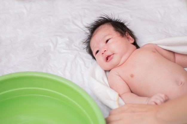 Asian baby taking bath. Newborn girl with bathing and water in the face.