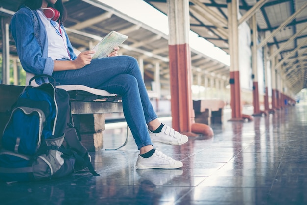 写真 アジアのバックパッカーの少女旅行者は、鉄道駅で待っている鉄道の地図を見ます。