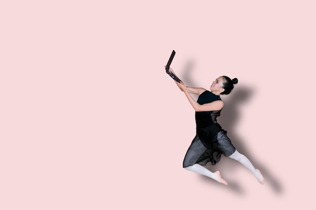 Photo asian ballerina holding a laptop on studio