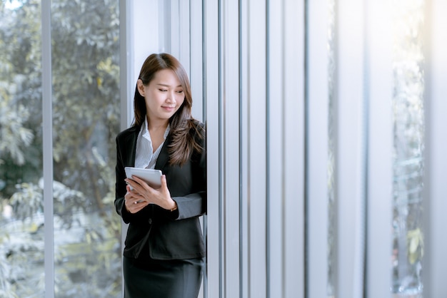 Asian beatiful young business woman in suit skirt using tablet to work about sales and marketing plan