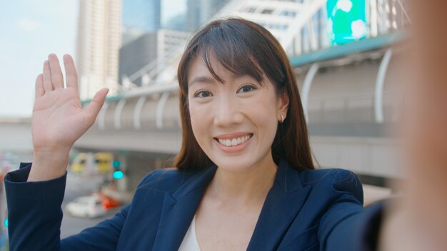 An asian beautiful business woman is making video call with colleagues or family in modern city , business cooperation and business technology concept.