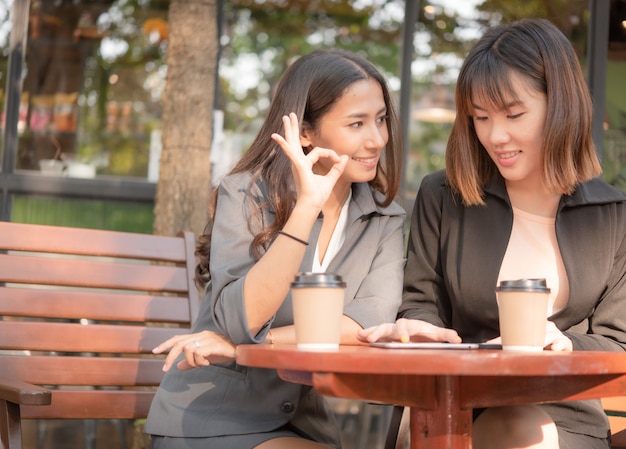 La bella donna asiatica di affari che lavora con la compressa e lo smartphone nel caffè del caffè comperano