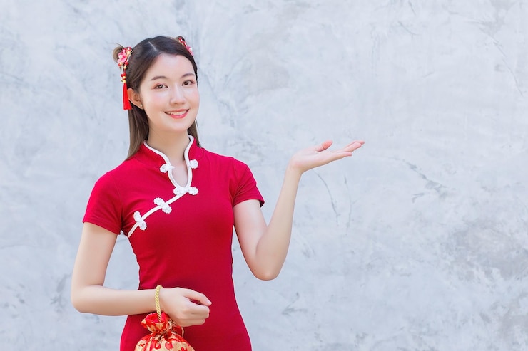 Photo 赤いドレスを着たアジアの美しい自信のある女性が、何かを提示するために手を指しています。