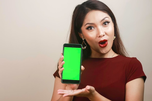 Азиатская красивая девушка потрясена смартфоном в красной рубашке