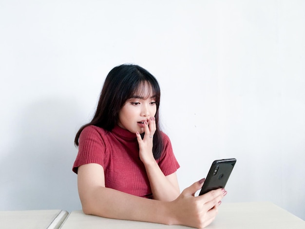 Asian beautiful girl is shocked in the smartphone on the isolated white background