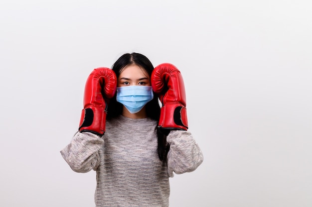 Asian beautiful happy young woman wearing mask protection and boxing gloves her get ready for Coronavirus fighting against, with copy space