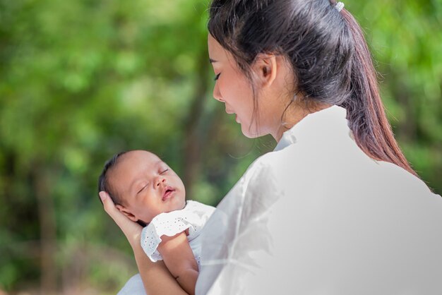 アジアの美しい母親が寝ている間に赤ちゃんを抱きしめます