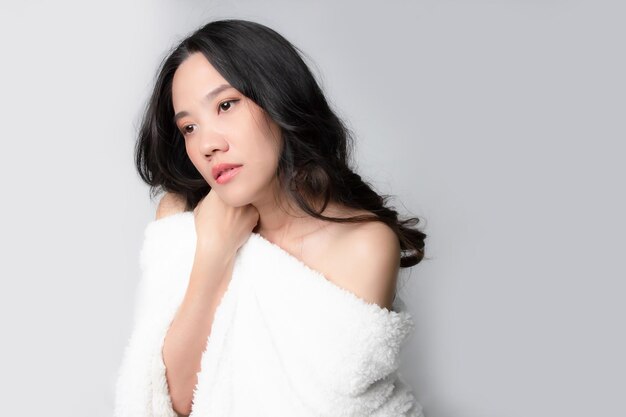 Asian beautiful woman cover with white fur blanket and show skin is looking away with thoughtful Mental heathy or skin care and beauty concept