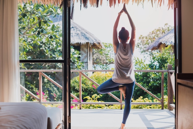 Una bella donna asiatica si esercita e gioca a yoga a casa. concetto di esercizio durante la quarantena a casa per prevenire l'infezione da coronavirus e covid-19.