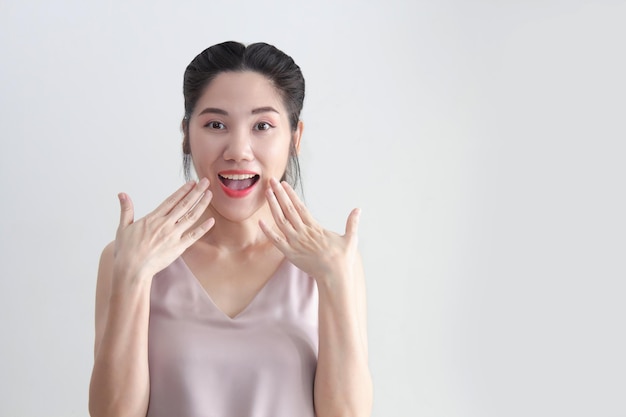 Asian beautiful woman raise both hand touch lips and smile with express a happiness and surprised