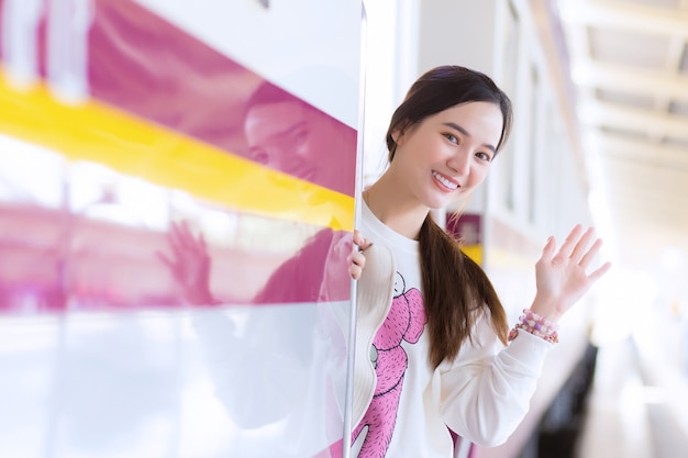 アジアの美しい女性は、電車で街で働いているために家族に別れを告げるか、駅に帰ってくると言います。