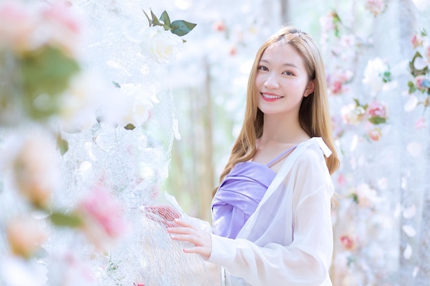 Asian beautiful woman smiles and stands in white rose flower garden as natural  luxury theme