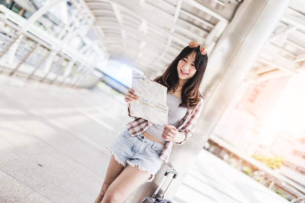 asian beautiful woman travel with backpack and suitcase with city background