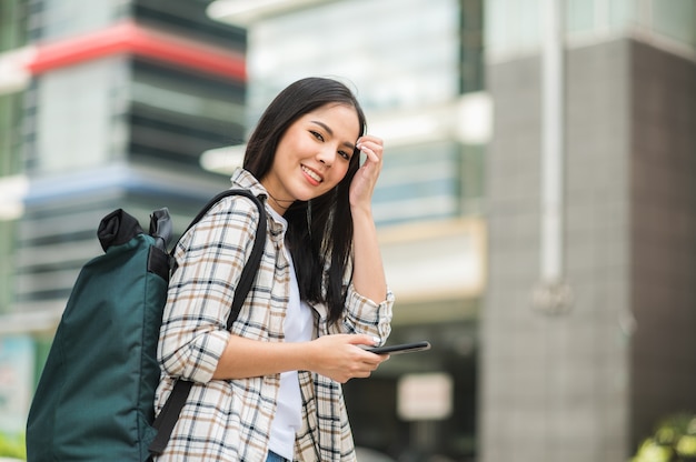 アジアの美しい女性旅行者は彼女の携帯電話を使用しています。