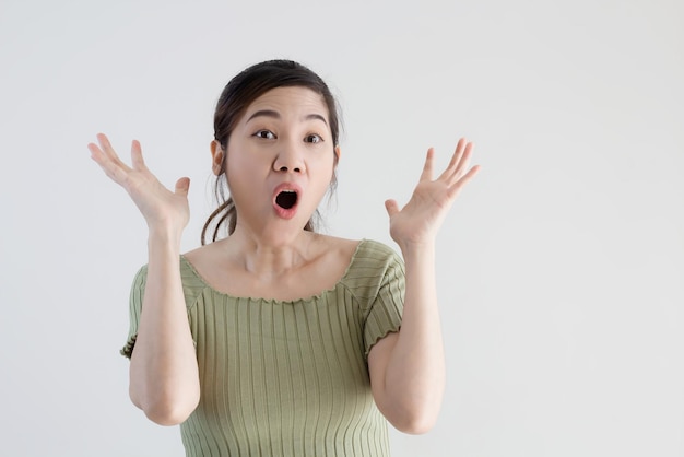La bella donna asiatica indossa una camicia verde scioccata e sorpresa dallo spazio della copia per una promozione e una pubblicità