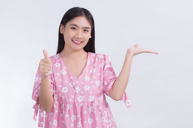 asian beautiful woman with black long hair in white shirt shows thumb up and present something