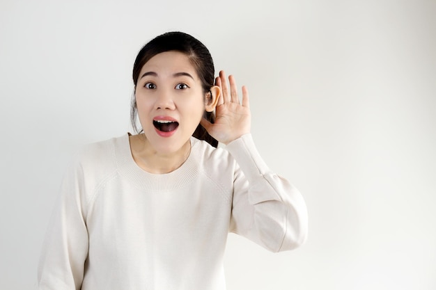 Le belle donne asiatiche usano l'orecchio della tazza della mano per ascoltare o ascoltare le notizie segrete, la promozione, i pettegolezzi, una pubblicità.