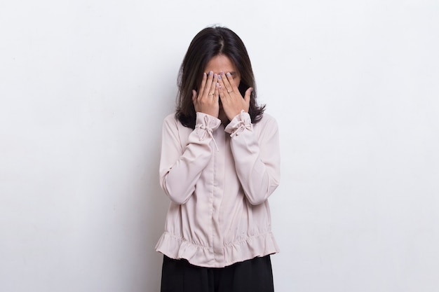 Asian beautiful young woman covers her face with her hands on white background