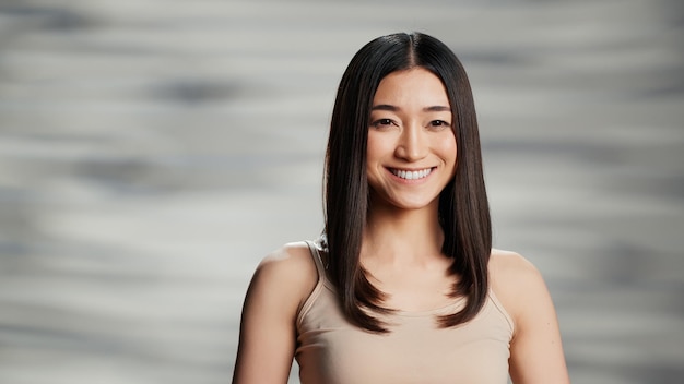 Asian beauty model posing for skincare ad in studio, woman with radiant and luminous skin feeling confident. Beautiful positive girl creating empowering, uplifting bodycare campaign.