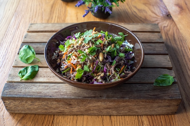 Asian beef salad with vegetables and nuts in a white bowl