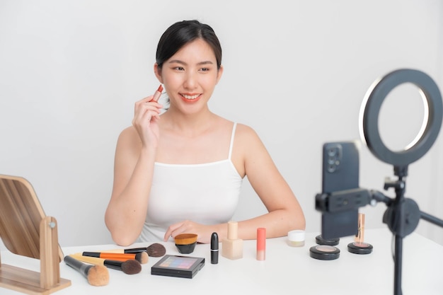 Фото Азиатская блогерка занимается макияжем и уходом за кожей в прямом эфире на своем мобильном телефоне через интернет