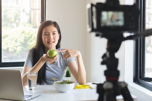 사진 녹색 사과를 먹고 비디오를 녹화하는 아시아 블로거