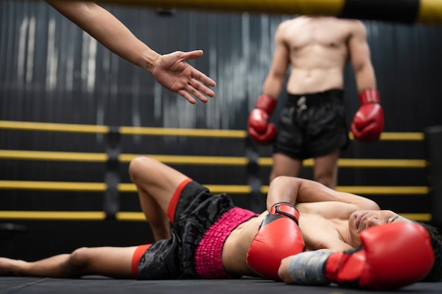 Asian boxer athlete man knocked out unconscious and lying down on floor center stage ring