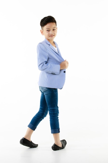 Foto ragazzo asiatico di 10 anni in blazer casual che cammina in modo intelligente e felice guardando la fotocamera su sfondo bianco isolato