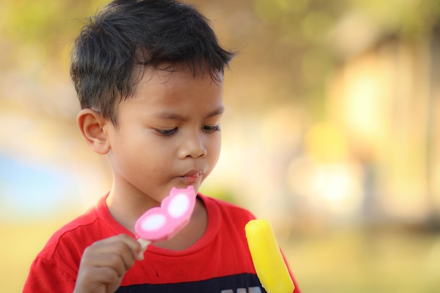 Il ragazzo asiatico mangia il gelato.