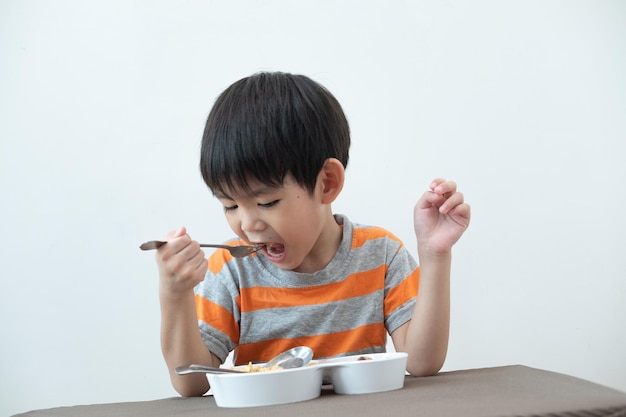 テーブルの上でヌードルを食べているアジアの少年