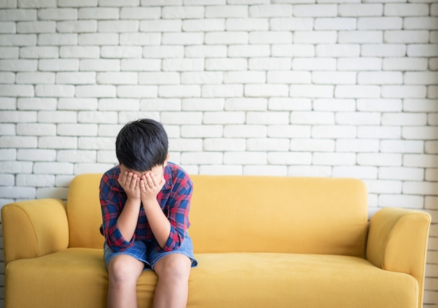 Asian boy feeling sad sitting on sofa