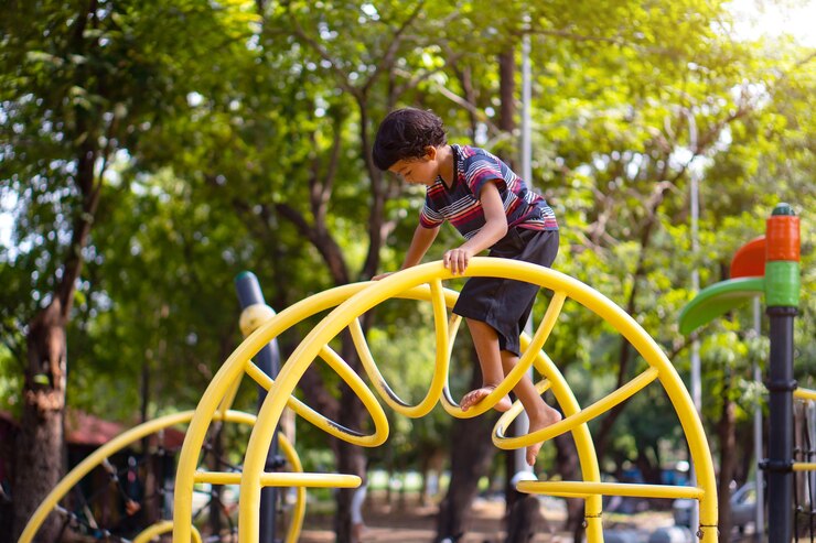 An Asian boy is climbing on a playground equipment in a school.
