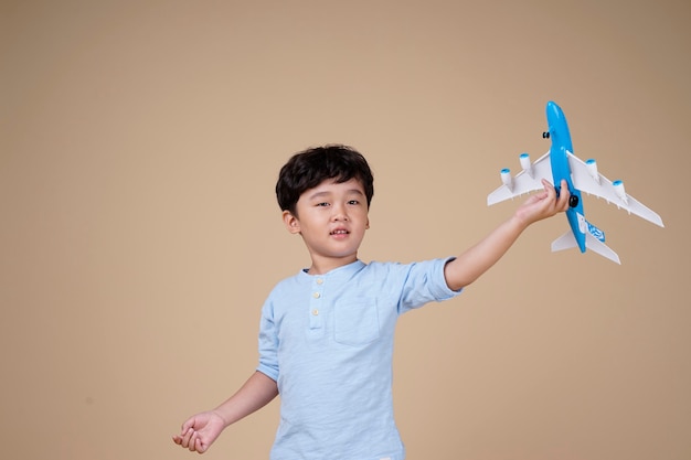 Asian boy is exciting to travel on airplane toy isolated on beige